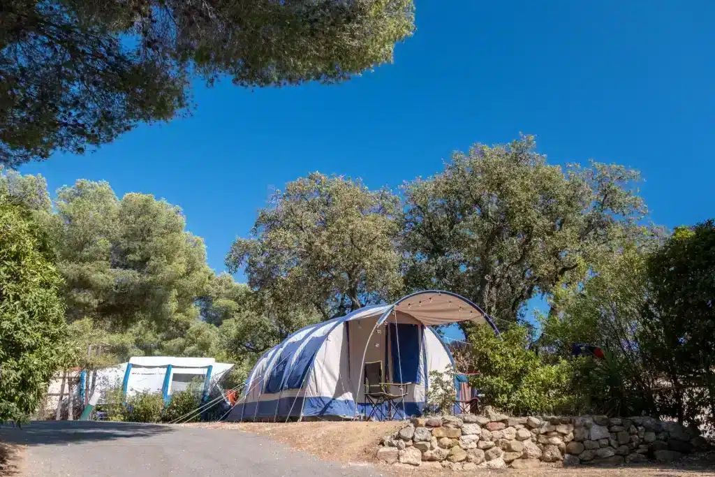 Tente de camping sous des arbres et ciel bleu