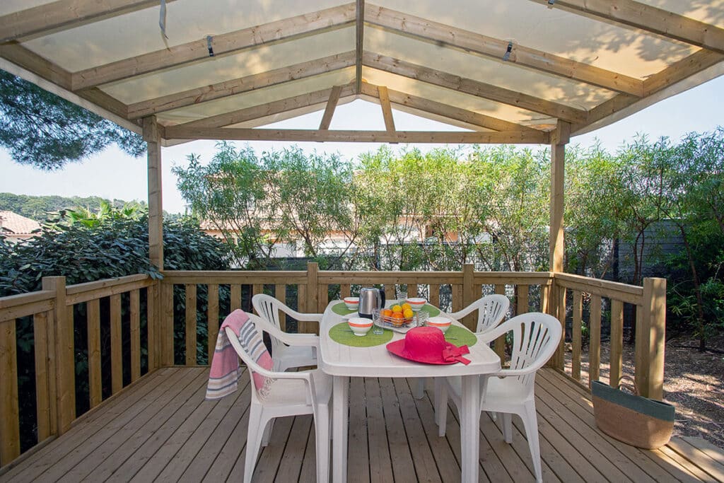 Terrasse en bois avec table, chaises et fruits.