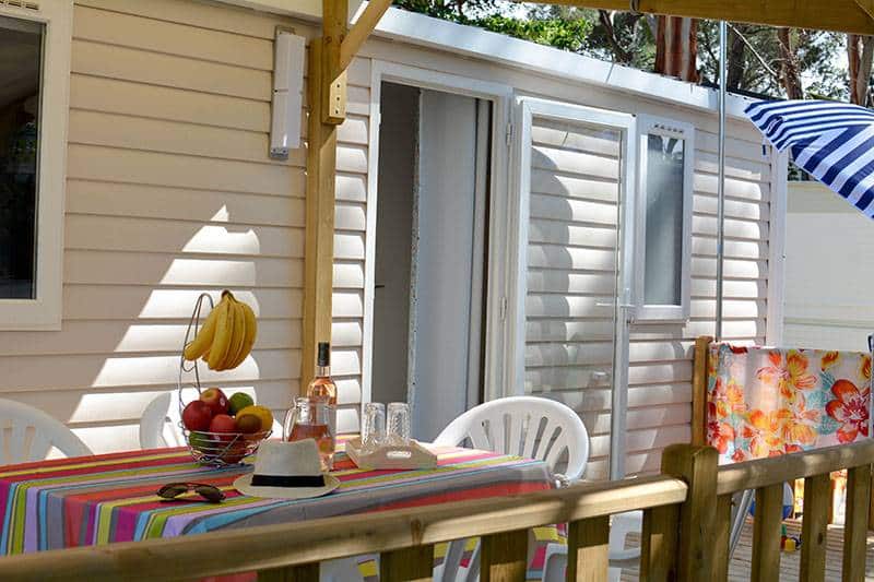 Terrasse de mobil-home avec table colorée et fruits.