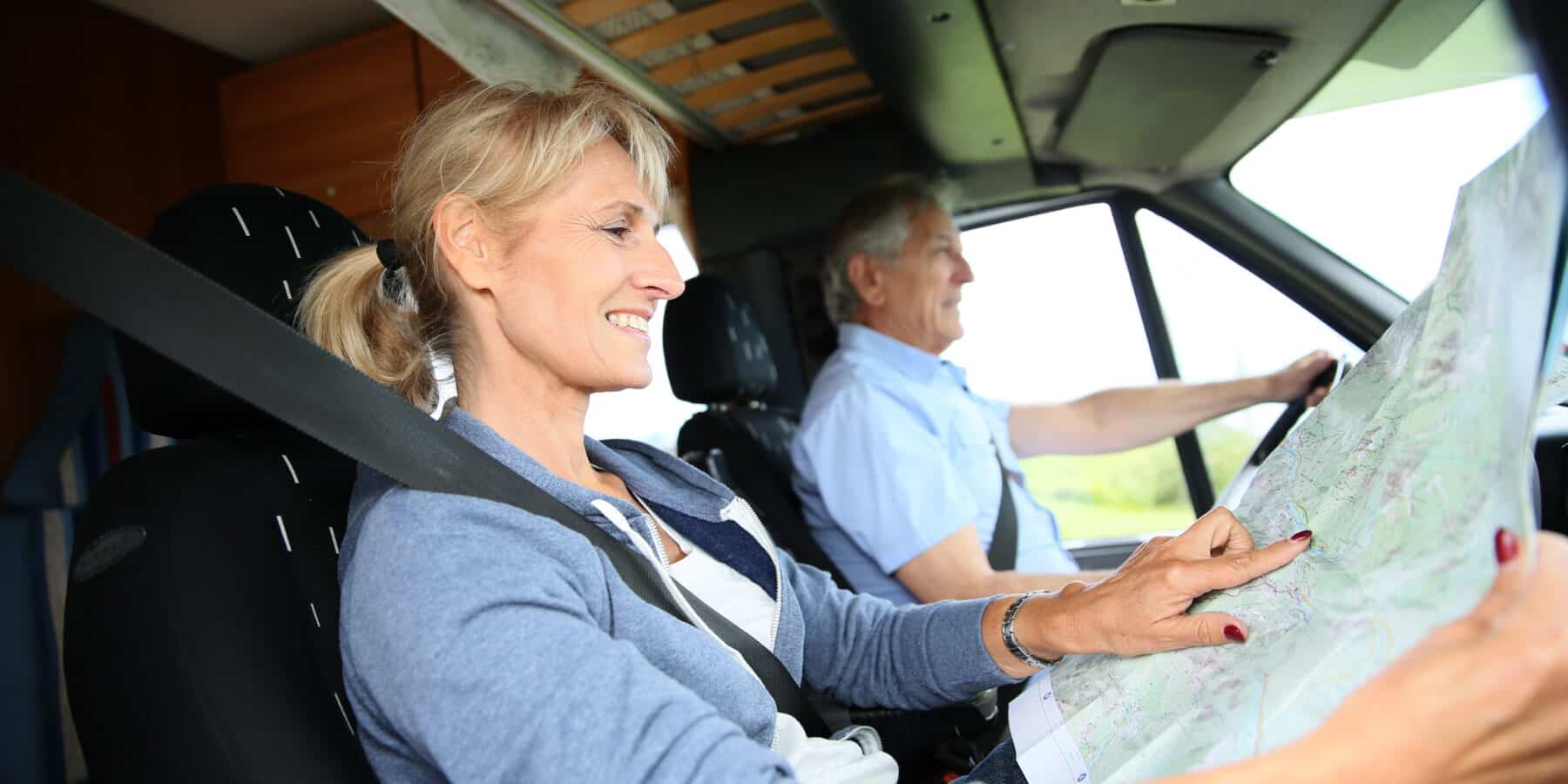 Senior couple riding camper and reading road map