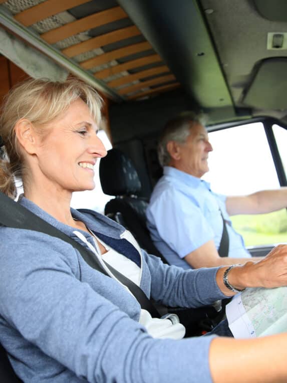 Senior couple riding camper and reading road map