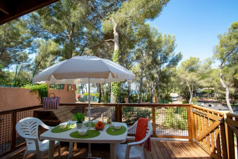 Terrasse en bois avec parasol et chaises blanches.